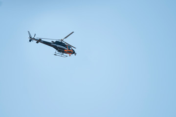 Orange and dark blue helicopter with video cameras flying with clear blue sky on background