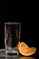 Glass and a cup of orange on a black background