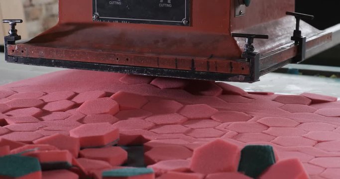 Heavy machine tool cuts out hexagonal workpieces from sheets of synthetic material, manufacturing paralon sponges for households, factory floor, automatic process, press, pressing, hexagonal shape
