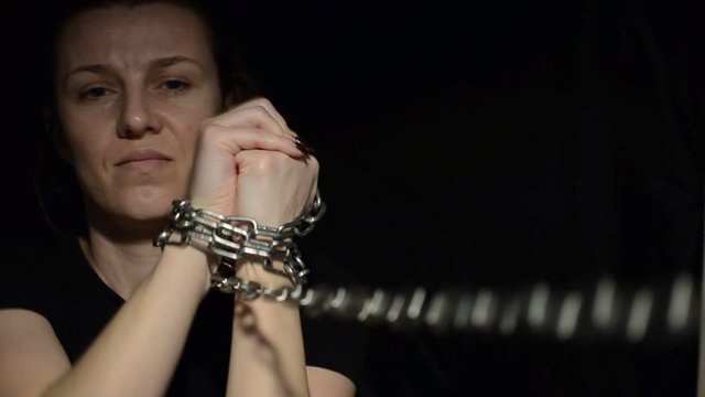 Young woman blindfolded in chains breaks out of them on a black background