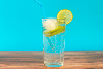 In a glass cup, cool mineral water with pieces of lime and ice.