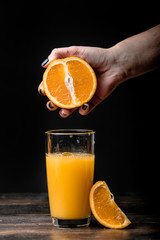 Orange juice is poured into a glass and a slice of orange on a black background