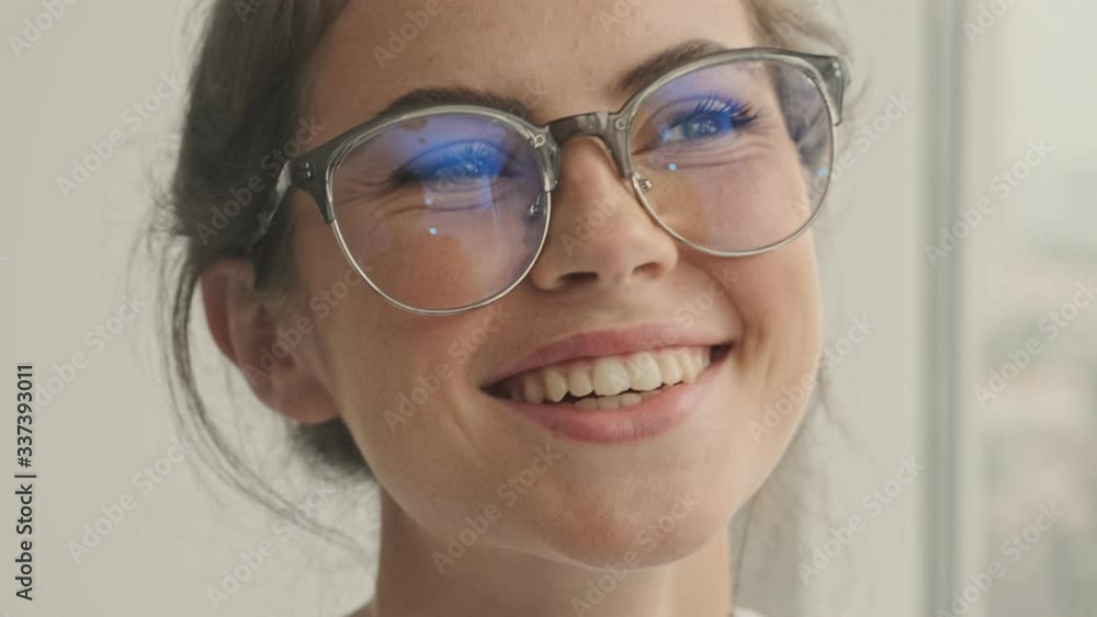 Sticker close up view of happy pretty brunette woman in eyeglasses looking at the camera and enjoying the mo