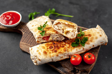 Burrito wraps with chicken and vegetables , against a background of concrete, 
 Mexican shawarma