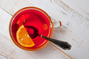 Glass cup with tea and lemon standing on a white painted wooden surface. Background for hot drinks....