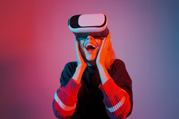 Young woman in VR glasses. A woman immersed in virtual reality makes movements with her hands. Blue...