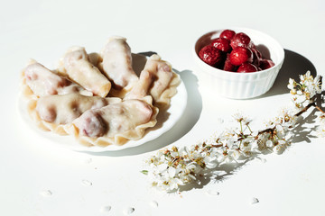 Cooked dumplings with cherries on white background.