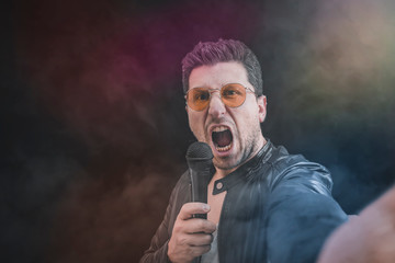 Young man sings screaming with microphone.