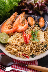Stir fried instant noodles with seafood in white dish.