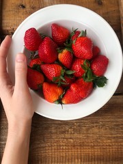 Juicy strawberries in a white plate on the table
