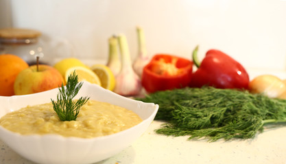 appetizing lentil porridge 
in a white dish, healthy eating background of various fruits and vegetables on a light kitchen countertop. Vegetarians. Lean food