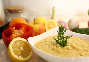 appetizing lentil porridge 
in a white dish, healthy eating background of various fruits and vegetables on a light kitchen countertop. Vegetarians. Lean food