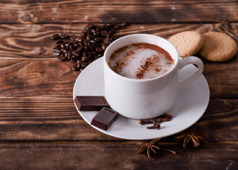 cap of coffee with foam,  cakes,  heart-shaped coffee beans on the wooden table.  Flat Lay with no people