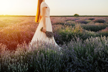 Romantic woman with bouquet of lavender in field having vacation in Provence, France. Girl admires...