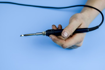 Soldering iron in a dirty working hand. Home work concept. Selective focus.