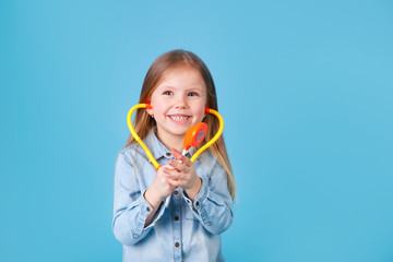 Portrait of a cute little girl with stethoscope on blue background