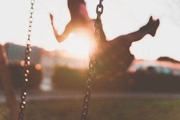 Girl having fun on the swing - young millenial woman relaxes in the park - freedom and well-being...