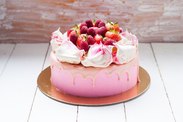 Pink cake with meringue, melted chocolate and fresh raspberries and strawberries.