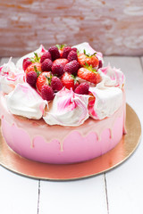 Pink cake with meringue, melted chocolate and fresh raspberries and strawberries.