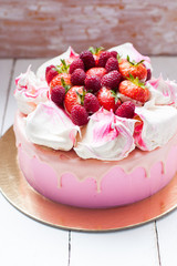 Pink cake with meringue, melted chocolate and fresh raspberries and strawberries.
