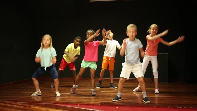 Positive children studying modern style dance in class indoors
