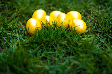 Golden color Easter eggs on the green grass. Side view. Easter 2020