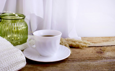Still life hygge kitchen details on desktop. Coffee cup, blanket and light glass on wooden desk....