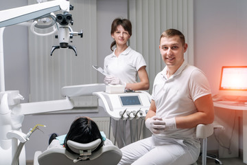 Fototapeta premium Professional dentist and nurse doing operation on female patient. A team of dentists with client in a dental office, oral care, healthy teeth, stomatology concept.