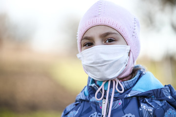 Closeup of the cute girl kid in the protective mask.