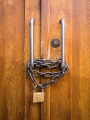A double-secured closed wooden door, with a conventional cylinder lock and a thick metal chain...