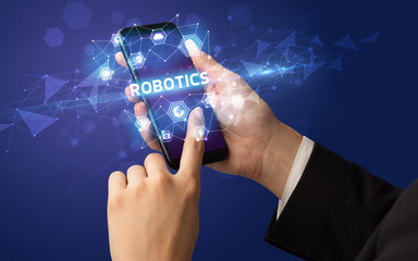 Female hand holding smartphone with ROBOTICS inscription, modern technology concept