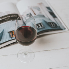 red wine glass and magazine on a wooden surface