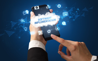 Female hand holding smartphone with SOFTWARE IMPLEMENTATION inscription, cloud technology concept