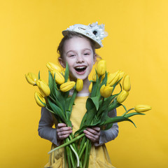 Beautiful little girl with a bouquet of yellow tulips