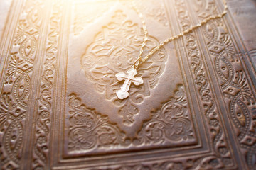 A cross with a yellow metal chain on the cover of an old religious book. Christianity, Orthodoxy.