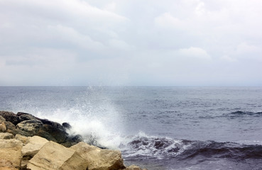 Seascape. Blue sky. Rocky beach. Sea. Waves are breaking on the shore. Bank is located on the left. Waves break on the shore. Spray. Copy space. Cyprus. Blue sky