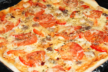 Homemade browned pizza with tomatoes just out of the oven.