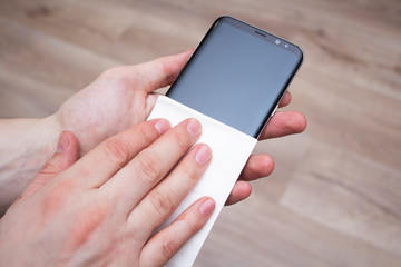 Disinfection of the phone screen, removing germs with antibacterial wet wipes for the prevention OF covid-19 coronavirus