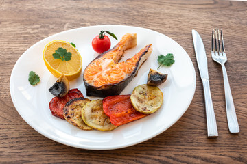 Grilled fish steak with vegetables on a white plate. A fish. Steak. Vegetables.