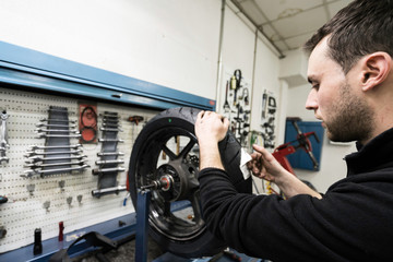 Mechanic repairs motorcycles at the workshop. Tire change.