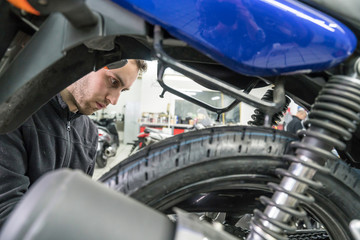 Mechanic repairs motorcycles at the workshop. Tire change.