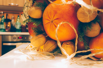Orange fruits oranges, grapefruit, tangerines, persimmons and walnuts are gathered in a beautiful bouquet, decorated with a luminous led garland for Christmas. A bouquet of fruit as a gift.