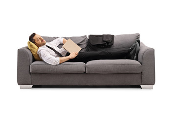 Businessman sleeping on a sofa with a book