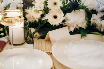 Festive table decorated with fresh flowers, candles, plates, forks and empty cards