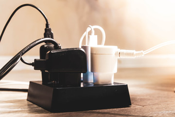 Beautiful stylish modern black extension cord for power supply of devices is on the floor. Square extension cord for electrical appliances. Plug is plugged into a surge protector, outlet.