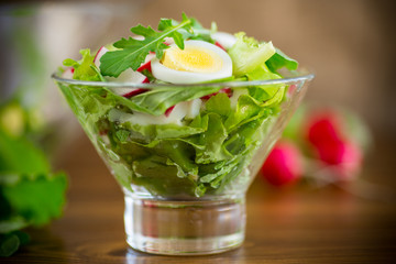 spring salad with arugula, boiled eggs, fresh radish, salad leaves in a glass bowl