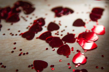 Background of small red hearts scattered on a wooden Board.