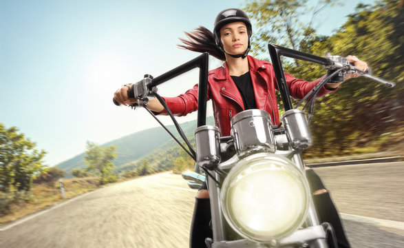 Young female biker riding a custom motorbike on road