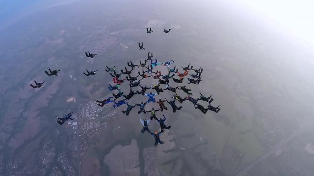 Large group skydiving formation in freefall, parachutists flying together in a coordinated aerial pattern. Concept of teamwork, precision, and achievement.