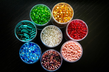 Obraz na płótnie Canvas Seed beads of different sizes in vials arranged as a flower in a top down perspective; A rainbow of colorful seed beads ready for beading